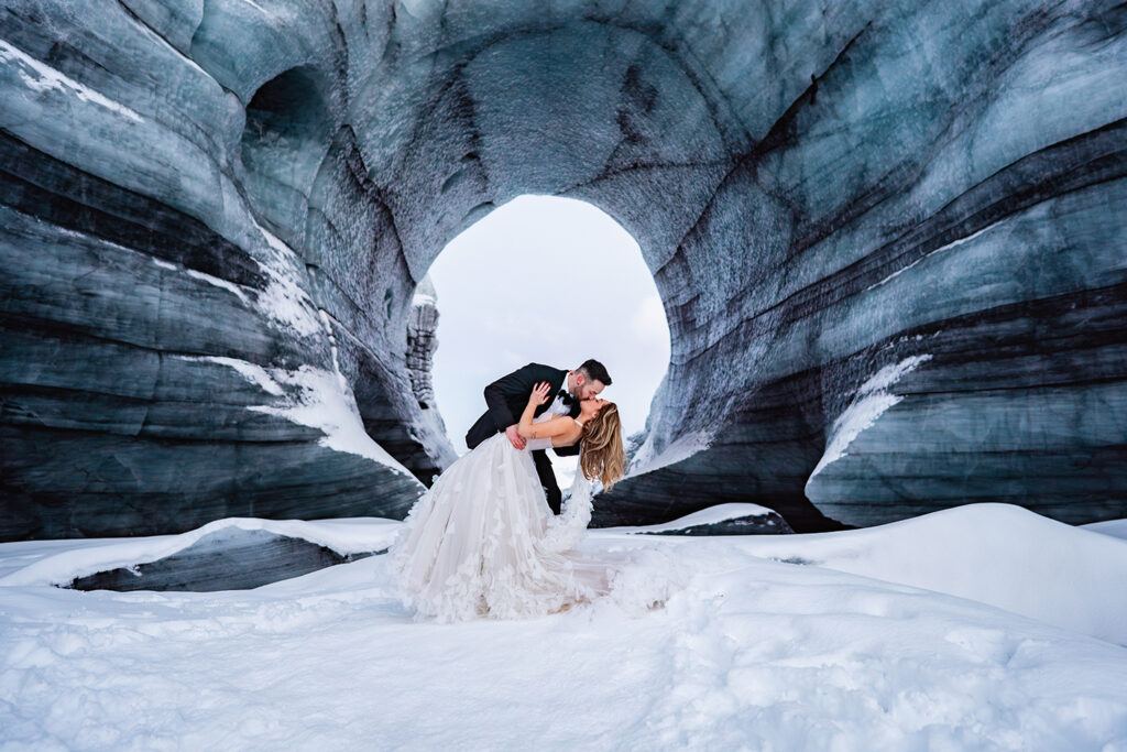 groom dips bride in kiss at Iceland Ice cave elopement photography