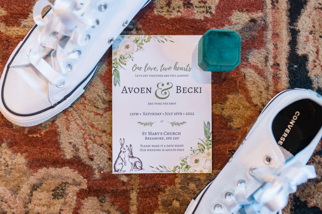 photo of a wedding invitation, the brides personalised converse and a ring box