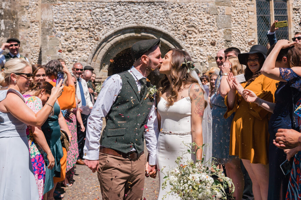 bride and groom smile at guests as they walk through eco-friendly confetti at church wedding