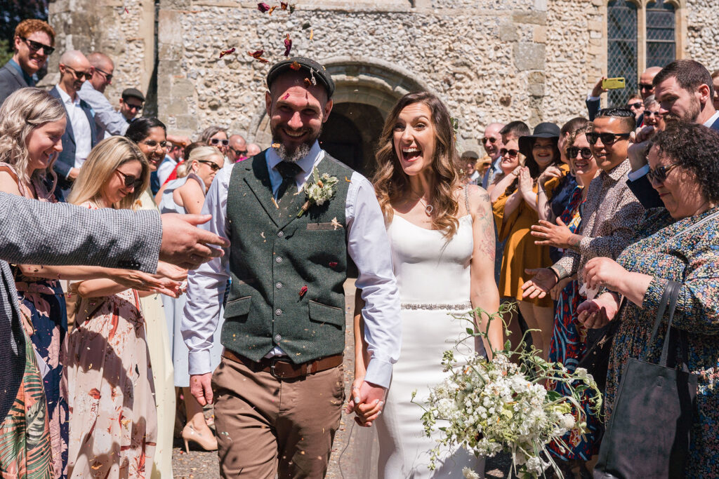 bride and groom smile at guests as they walk through eco-friendly confetti at church wedding