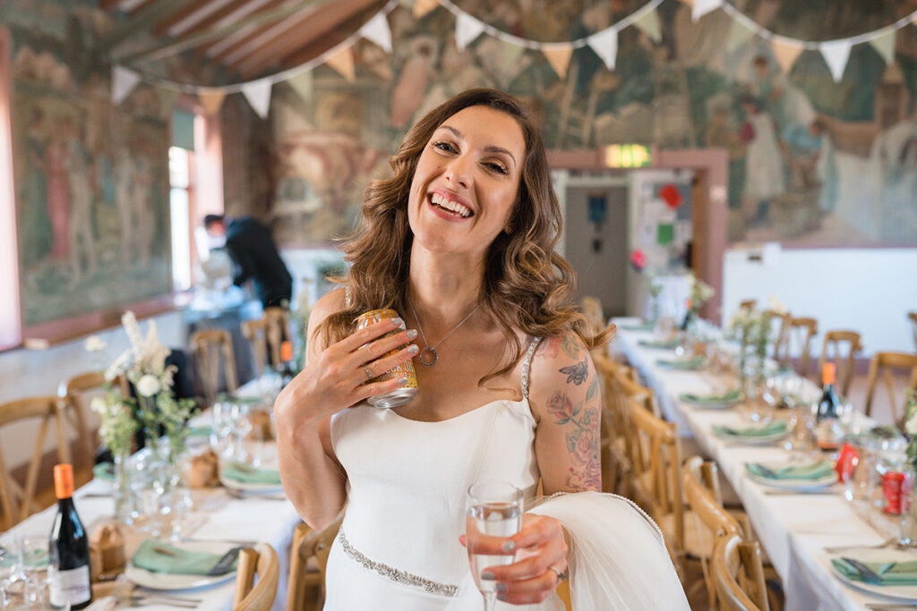 bride laughs as she cools herself down with can of beer