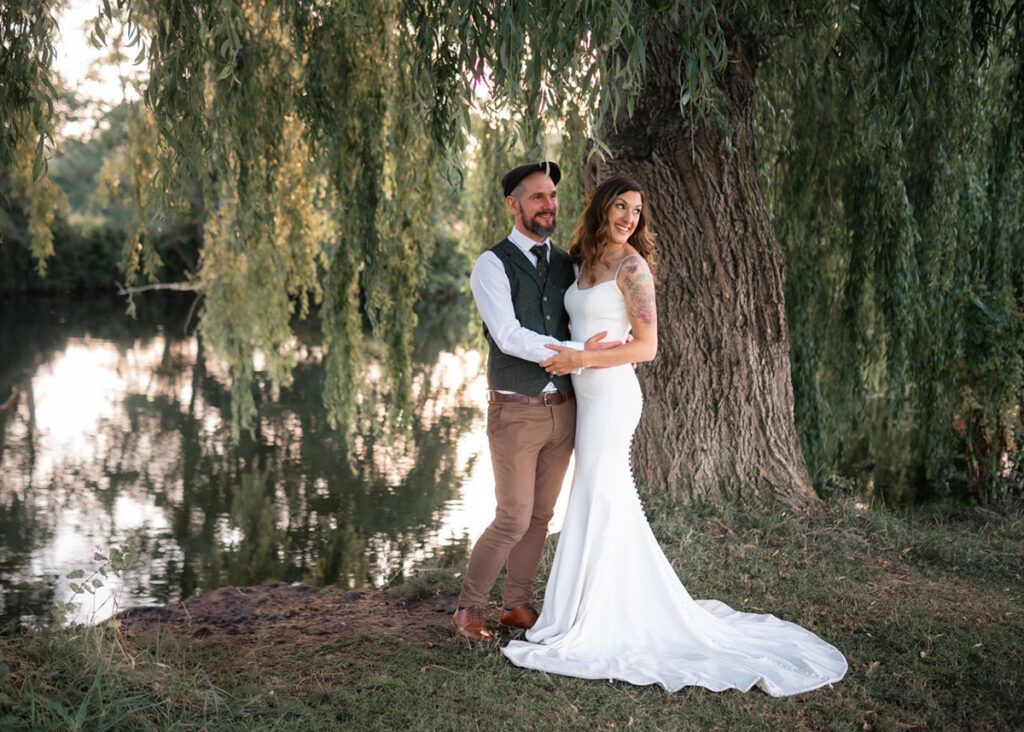 Bride and Groom embrace underneath a willow tree alongside the river Avon