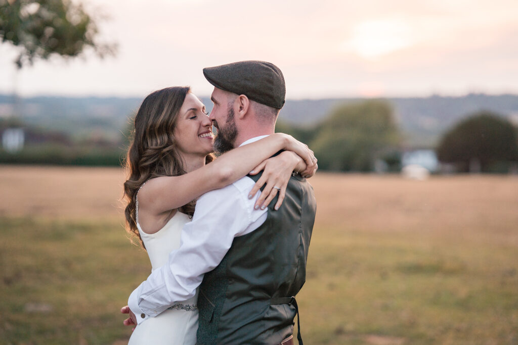 bride and groom embrace and smile at eachother during their wedding photos