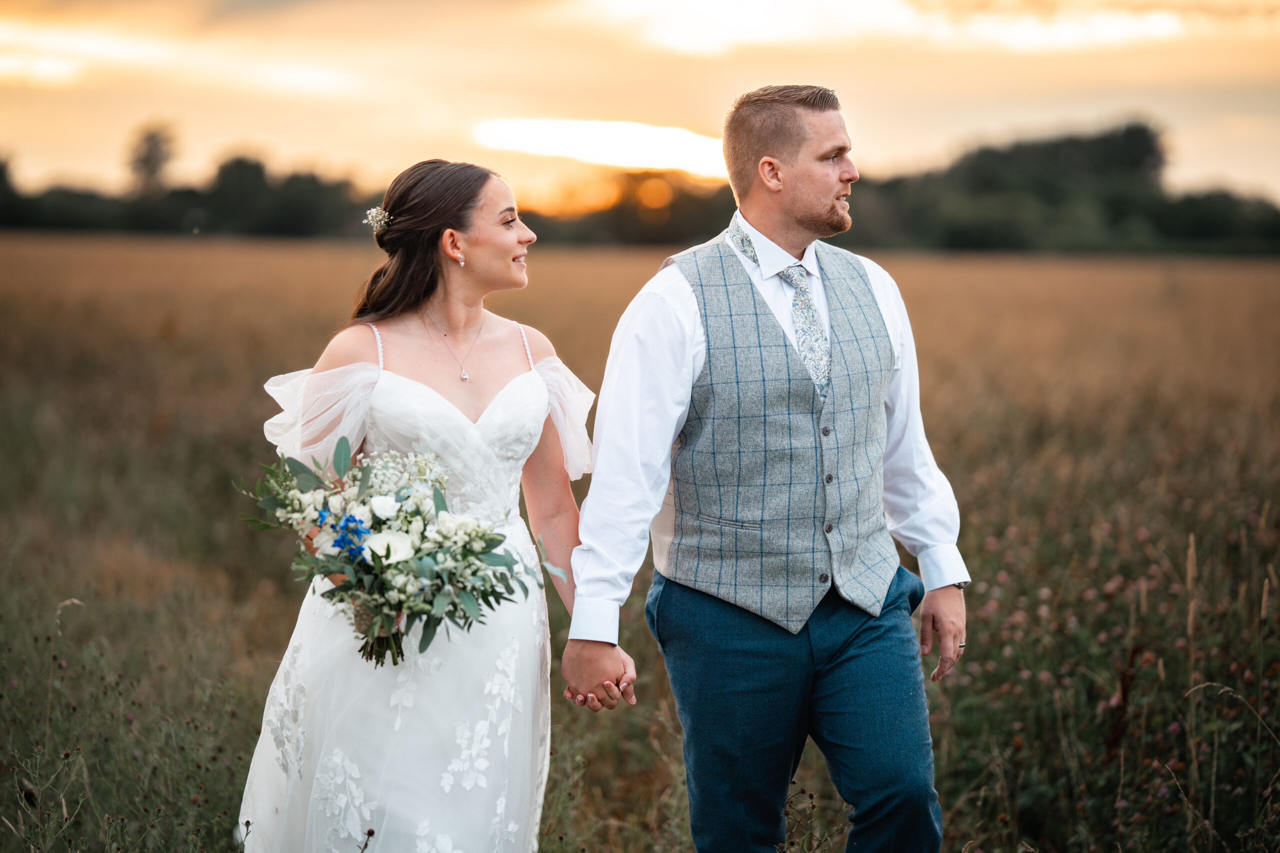 Bride and groom kiss at sunset in the field at Southend Barns