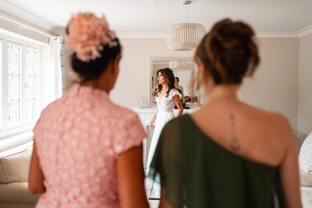 mother and daughter look on as bride is ready for wedding 
