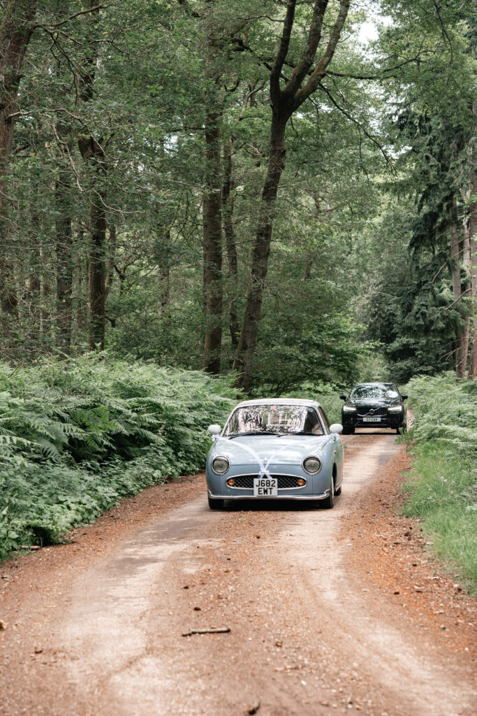 Vintage car driving through trees at Harewood Forest Wedding 
