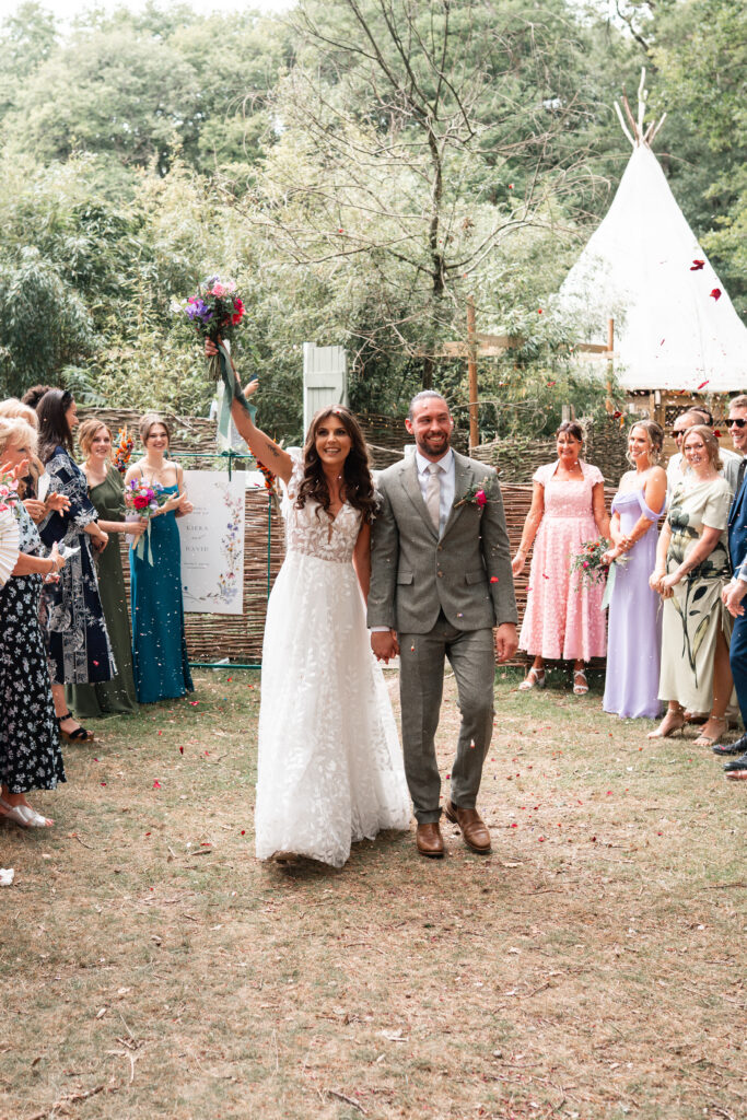 Bride and Groom walk through confetti outside Harewood Forest Weddings 