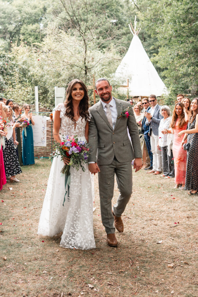 Bride and Groom walk through confetti outside Harewood Forest Weddings 