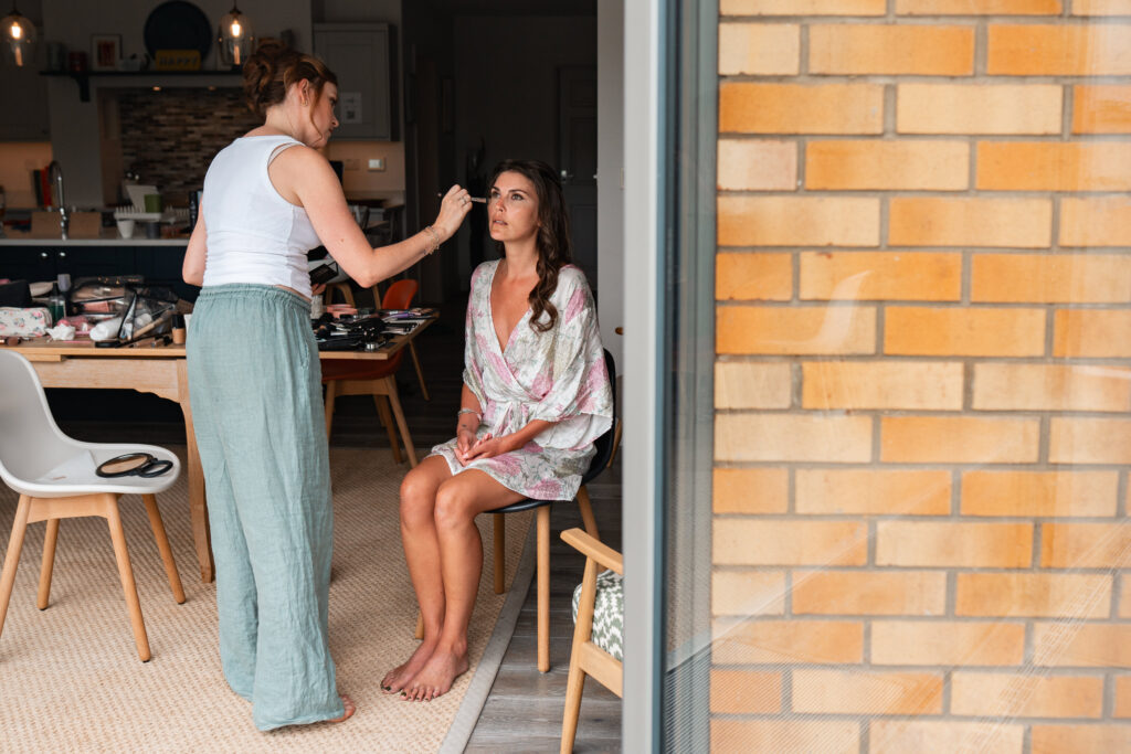 woman sat having makeup done on wedding morning