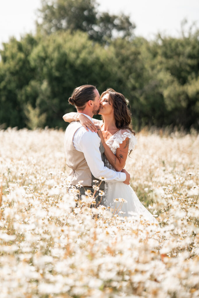 Bride and Groom kiss in field of wildflowers at Harewood Forest 