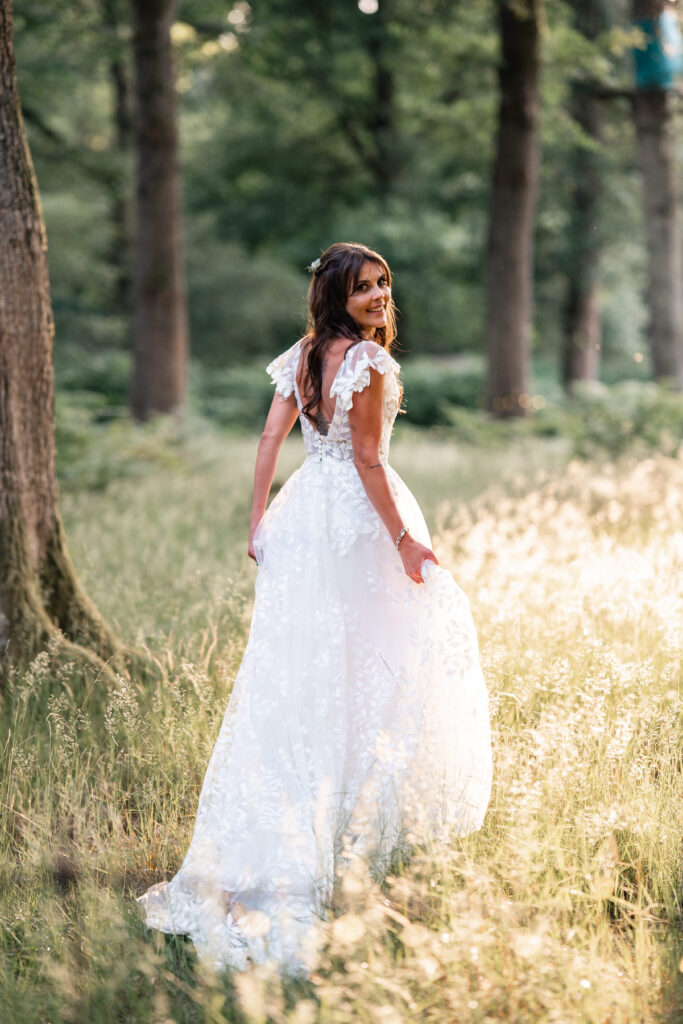 Bride looks over shoulder in floral dress in Harewood Forest 