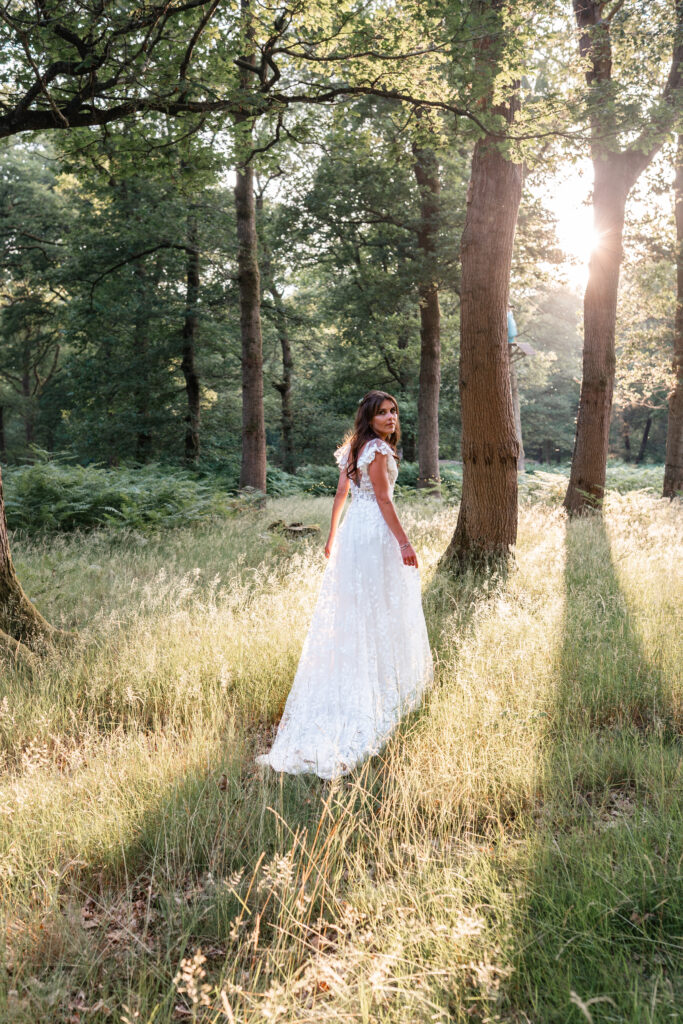Bride looks over shoulder in floral dress in Harewood Forest 