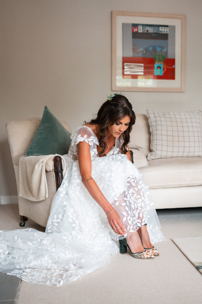 bride ties her heeled shoes in wedding dress