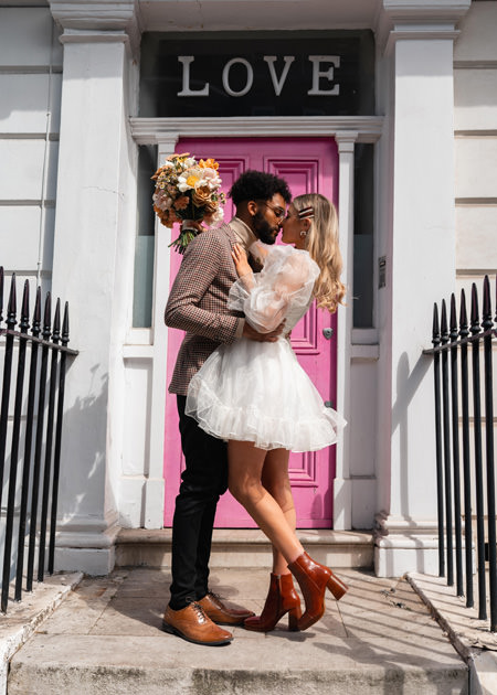 Couple kiss in front of icon pink door at chelsea wedding