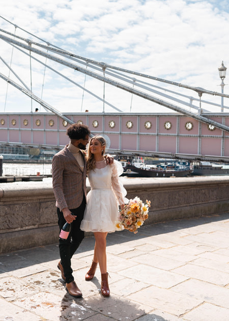 couple walk along river thames at london wedding