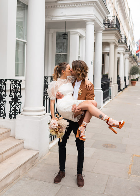 Groom carries bride through streets in london wedding