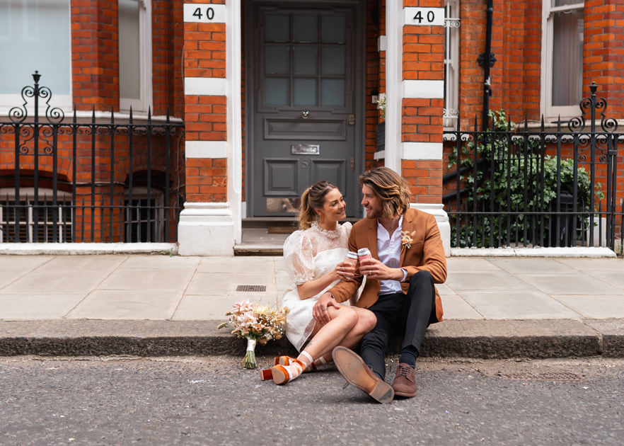 Newly Weds sit on curb in Chelsea after wedding
