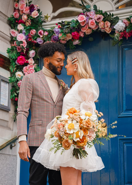 newly married couple stand in front of blue door at chelsea town hall wedding