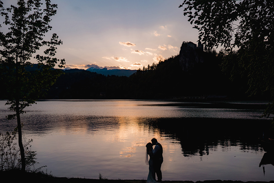 couple in silhouette kissing in front of lake bled at sunset