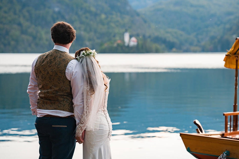 bride rests head on grooms shoulder overlooking Lake Bled at Sunset